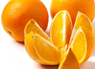 sliced and whole oranges over white