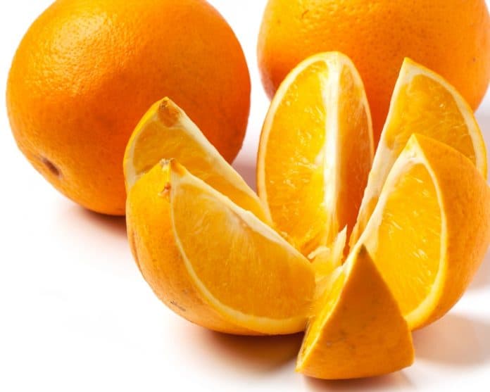 sliced and whole oranges over white