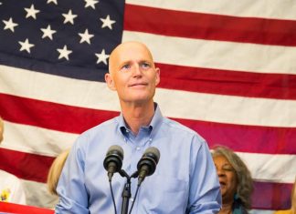 rick scott in front of an american flag