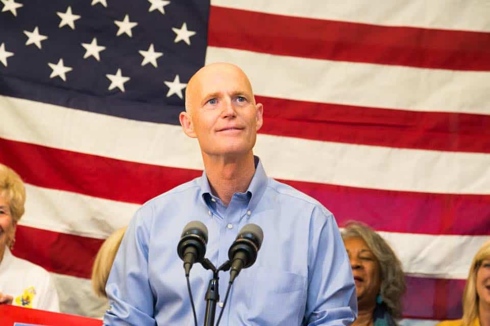 rick scott in front of an american flag